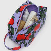 Baggu cosmetic Dopp Kit bag with red apple pattern containing toiletries on a white background
