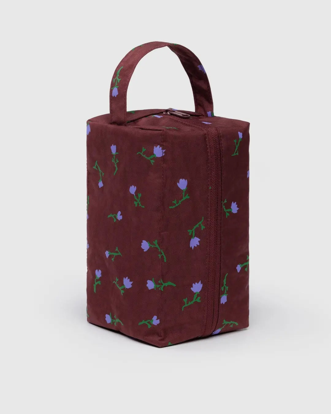 baggu dopp kit with painted purple flowers on a burgundy recycled nylon background standing on one end showing the zipper closure and loop for carrying or hanging
