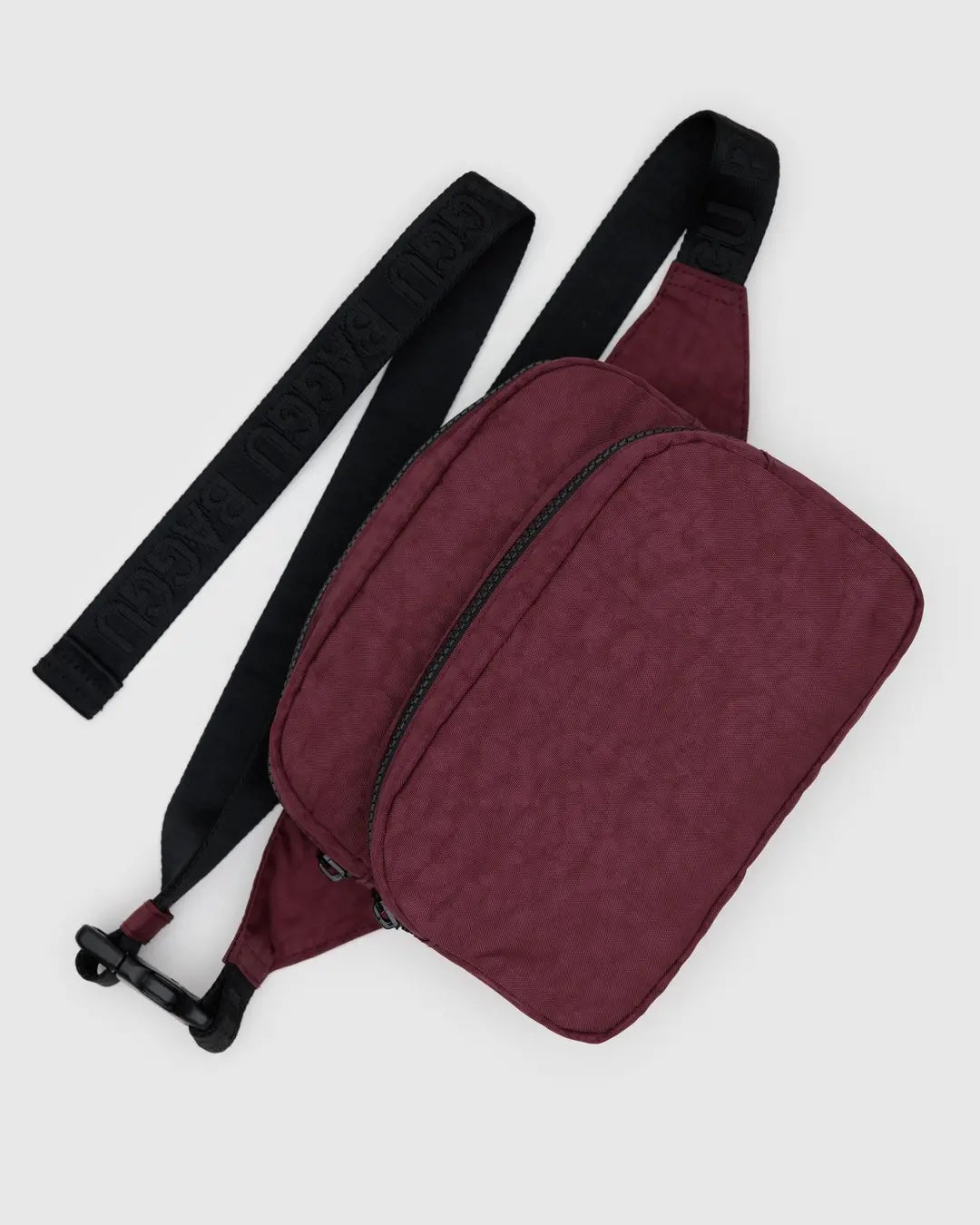 Mahogany red Baggu double compartment fanny pack crossbody bag with a black strap and zippers on a light gray background