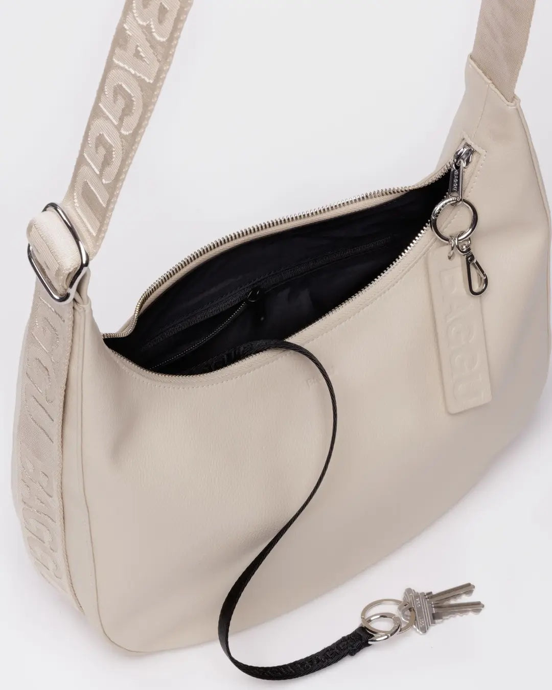 Stone Baggu leather medium crescent bag with open top showing black interior, keychain, and visible branding details