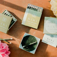 two open boxes of hibi incense matches on a terra cotta background with dahlia flowers