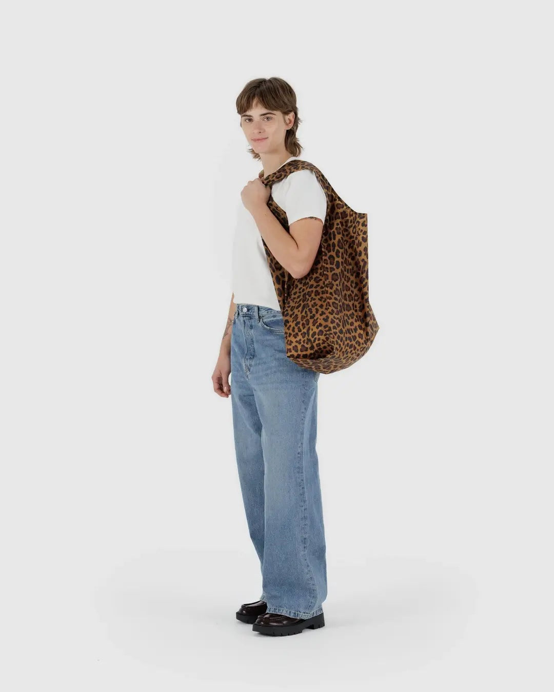 Person holding a leopard print Baggu reusable bag against a white background