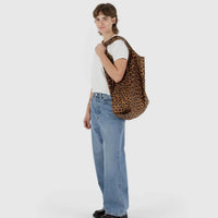 Person holding a leopard print Baggu reusable bag against a white background
