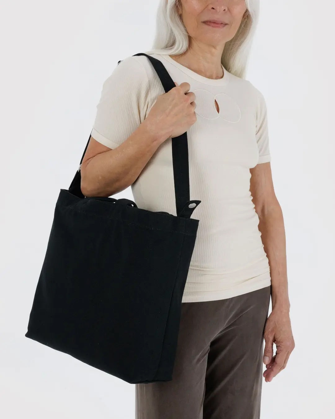 Person holding a black baggu canvas tote bag against a white background