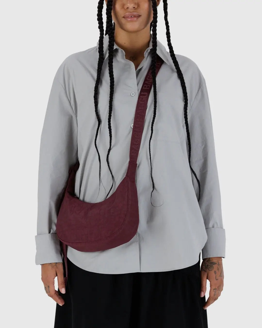 a person with a grey shirt and black bottoms on is shown wearing a mahogany baggu small crescent bag cross body