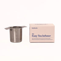 Metal tea infuser with packaging on a white background