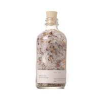 A clear glass bottle with a cork stopper, labeled 'Soaking Salts - Thrive' by Well Kept.