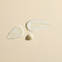 Three droplets of Wildcraft Calm Lotion to show the lightweight texture of the product on a beige background