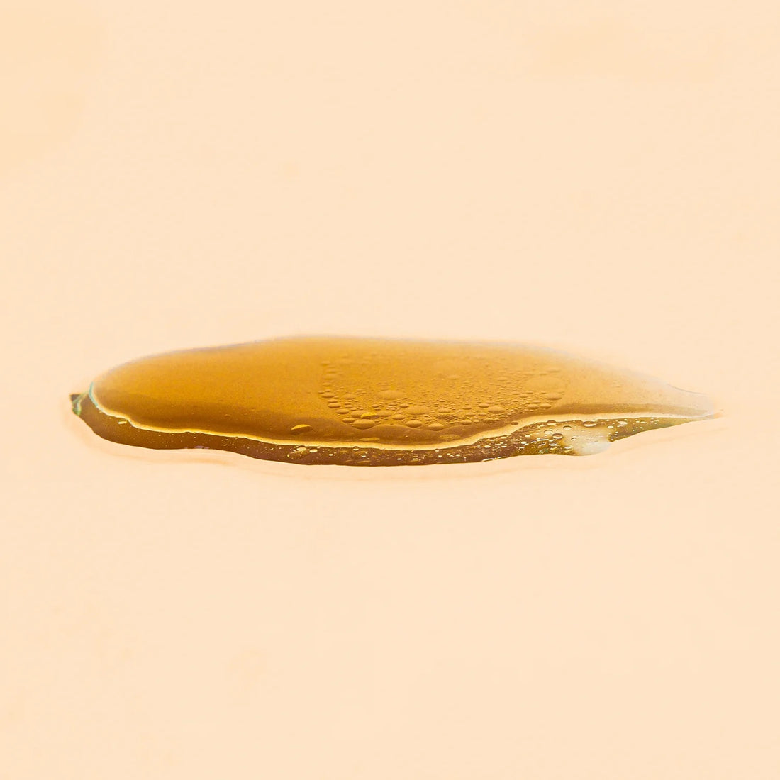 Close-up of Wildcraft Cleanse Purifying Tonic & Makup remover that looks like a pool of honey on a beige background