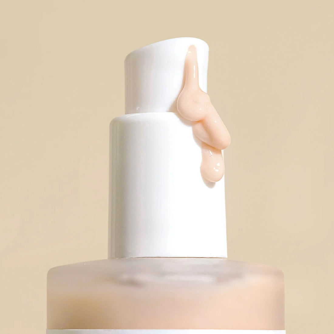 up-close shot of a white pump bottle with a pump of wildcraft Resurfacing Cream Cleanser oozing down the bottle. The product is a light pink colour with a creamy texture that looks very luxurious