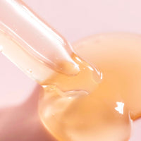 a close-up image of a pipette dispensing Three Ships Jelly Drops Kaduku Plum + Mushroom Hyaluronic serum onto a pale pink surface to show the jelly-like texture of the product