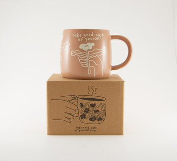 A light terracotta colour ceramic mug by People I've Loved with cream simplistic flower print and text "take good care of yourself"