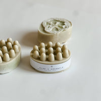 three aloe & coconut massage soap bars on a beige background showing the loofah inside the soap