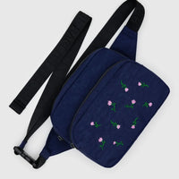 Baggu Navy blue crossbody fanny pack bag with pink wildflower embroidery and black adjustable strap on a light grey background