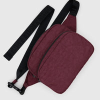 Mahogany red Baggu double compartment fanny pack crossbody bag with a black strap and zippers on a light gray background