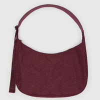 a large baggu nylon crescent bag in mahogany red with matching strap against a pale grey background