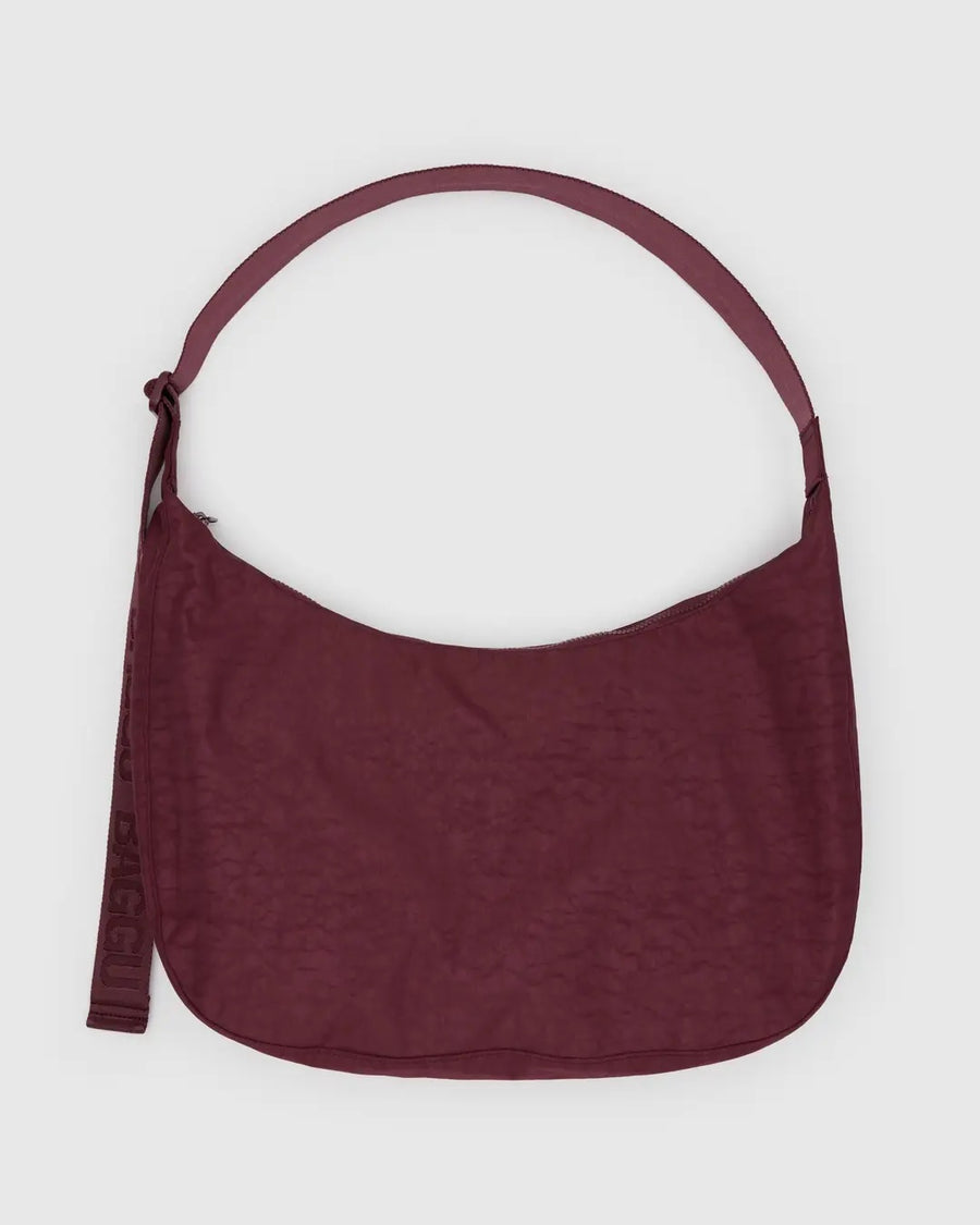 a large baggu nylon crescent bag in mahogany red with matching strap against a pale grey background