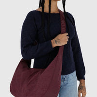a person wearing a blue sweater and pale denim jeans is shown wearing a large Baggu crescent bag crossbody