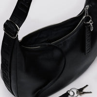 Black leather Baggu medium crescent bag close up showing keychain and other high quality finishing details