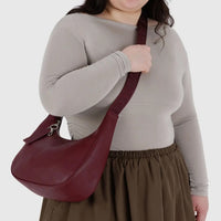 person with long dark hair, wearing grey fitted top and khaki skirt is shown with a medium baggu leather crescent bag being worn crossbody