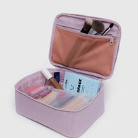 Open Baggu dusty pink cosmetic case with makeup items on a light gray background