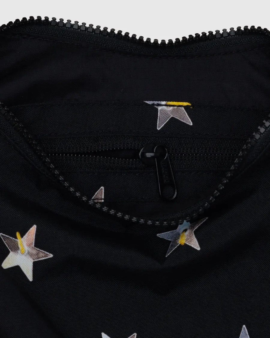 Close up image of a Baggu small black crescent bag with silver star print. Stars appear as though they are sewn on sequins. 