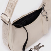 baggu small recycled leather crescent bag in 'stone" showing close up details of the matching strap, key chain holder and silver hardware