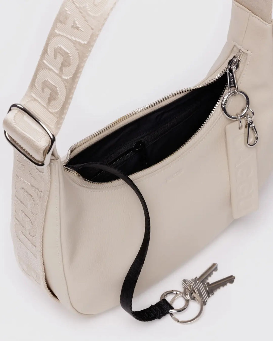 baggu small recycled leather crescent bag in 'stone" showing close up details of the matching strap, key chain holder and silver hardware