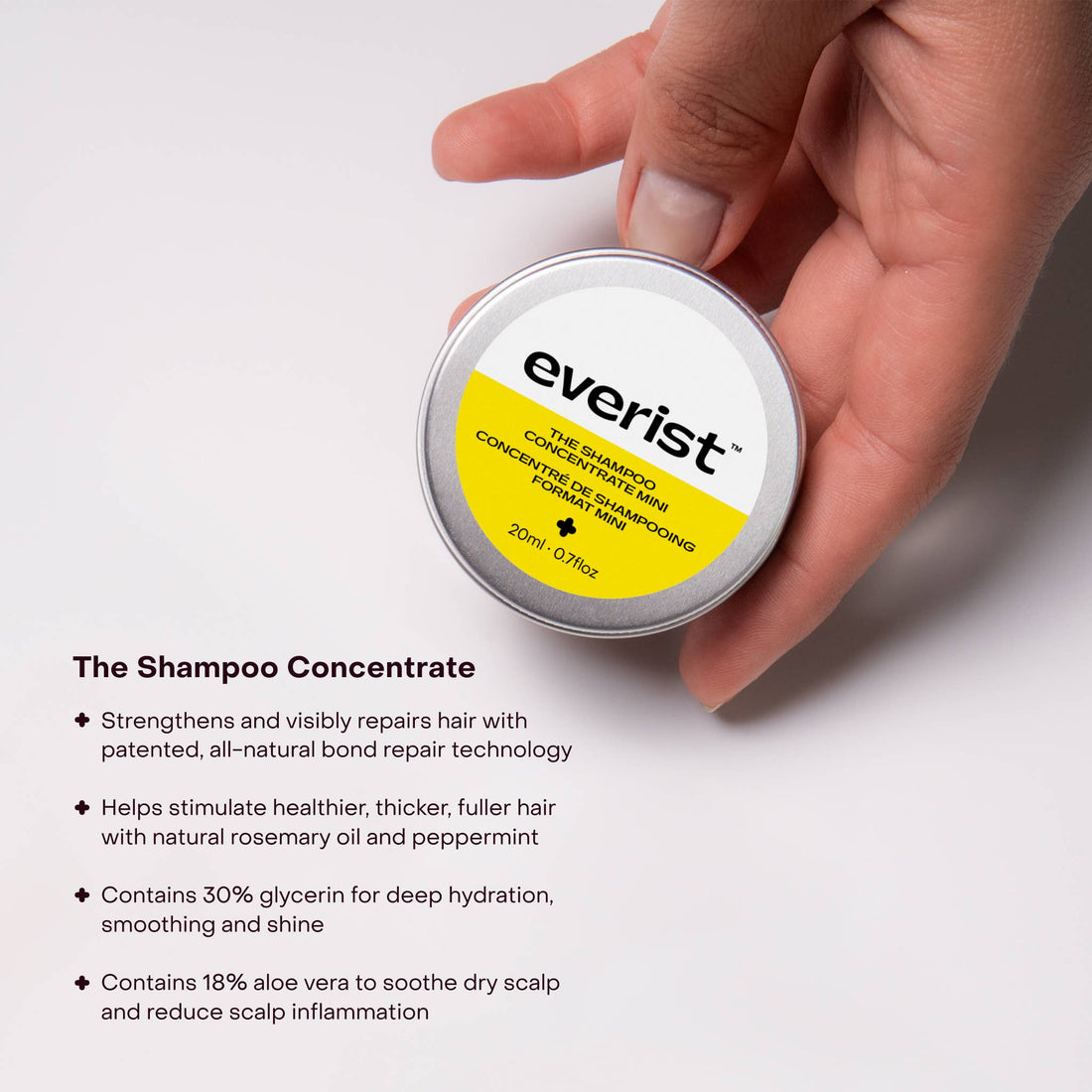 Hand holding a container of Everist shampoo concentrate with product details on a white background