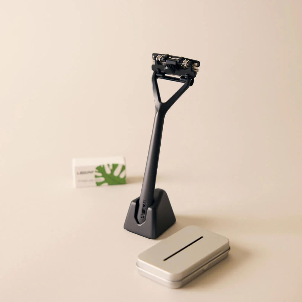 Black razor with stand and silver case on a beige background