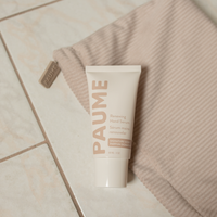 Tube of PAUME cream on a towel on a tiled floor
