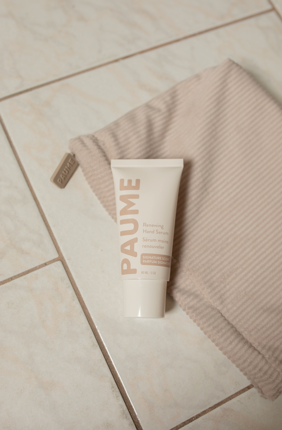 Tube of PAUME cream on a towel on a tiled floor