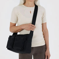 Person wearing a black baggu cargo crossbody bag on a white background