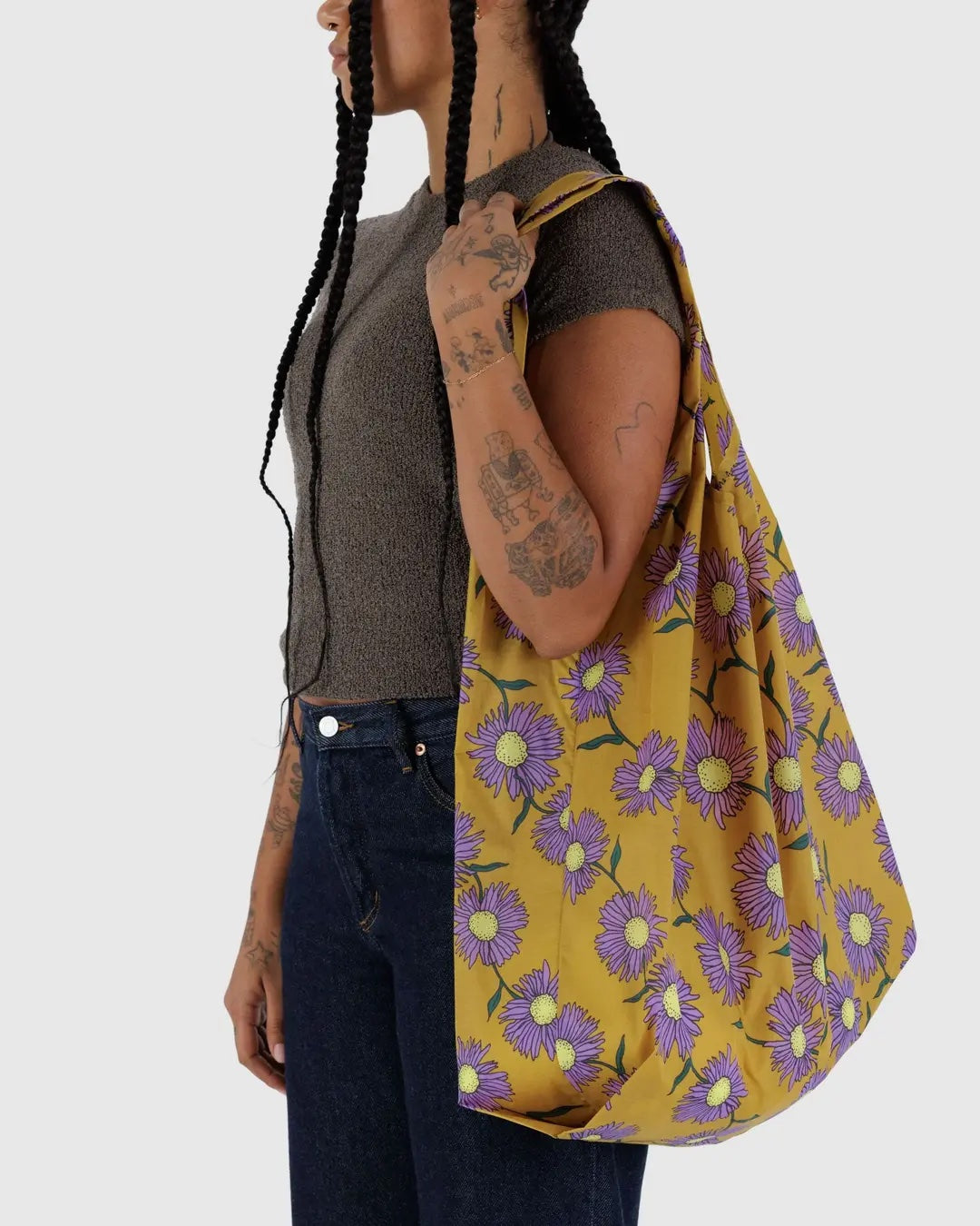 Person holding a Big Baggu yellow floral-patterned bag against a white background