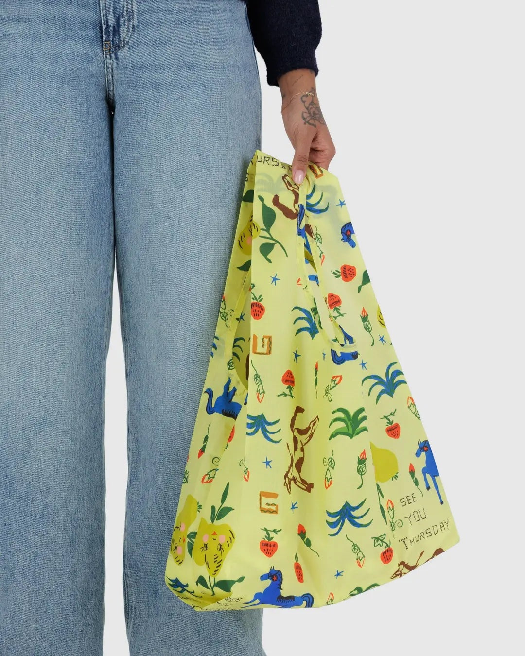 a person from the waist down is shown holding a painted prairie standard baggu reusable bag