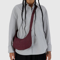 a person with a grey shirt and black bottoms on is shown wearing a mahogany baggu small crescent bag cross body