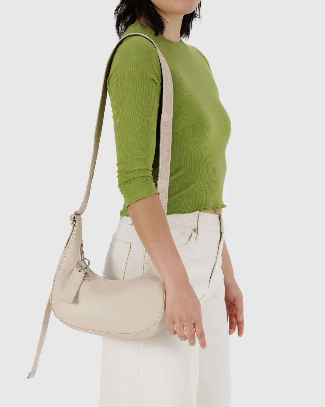person wearing a stone coloured small baggu recycled leather crescent bag on their shoulder