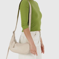 person wearing a stone coloured small baggu recycled leather crescent bag on their shoulder
