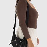 Person wearing a black baggu crescent with star patterns against a white background