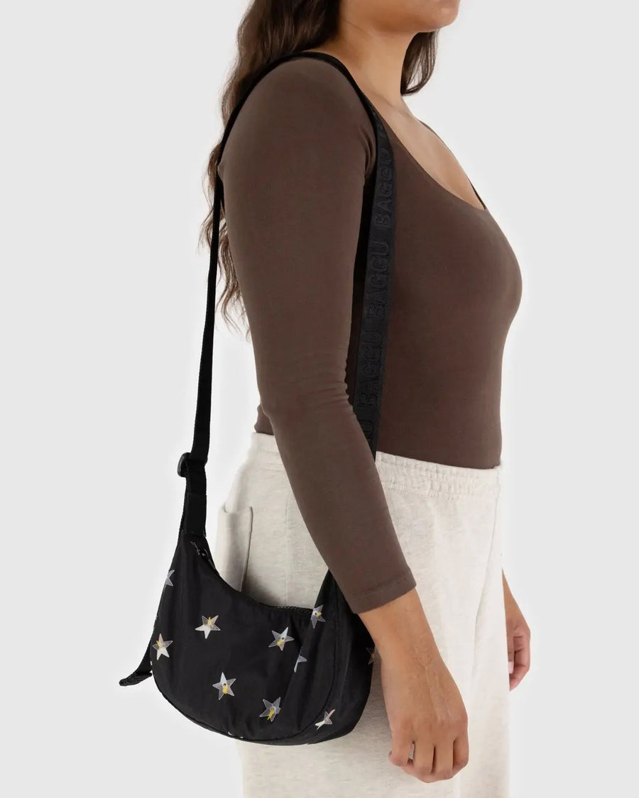 Person wearing a black baggu crescent with star patterns against a white background