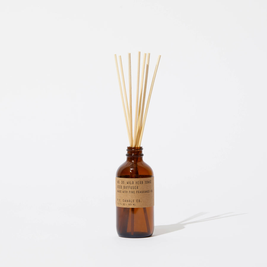 P.F. Candle Wild Herb Tonic reed diffuser in amber glass diffuser bottle with wooden sticks on a white background