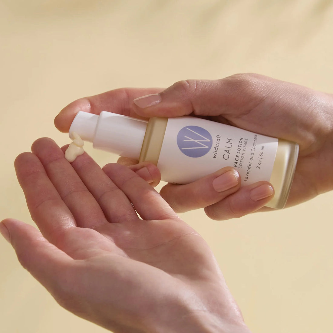 Hands holding a bottle of Wildcraft Calm lotion against a beige background