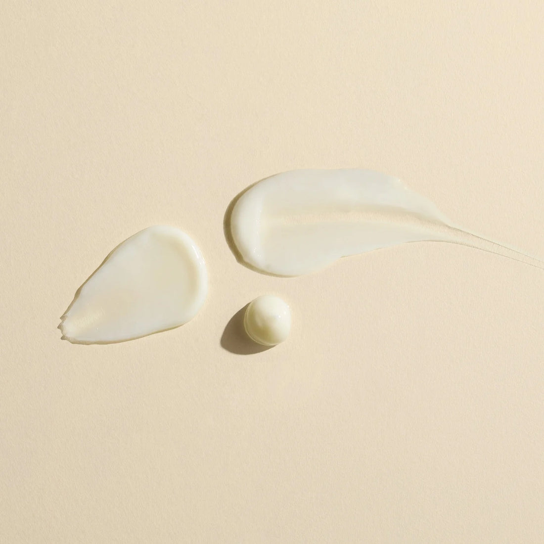 Three droplets of Wildcraft Calm Lotion to show the lightweight texture of the product on a beige background
