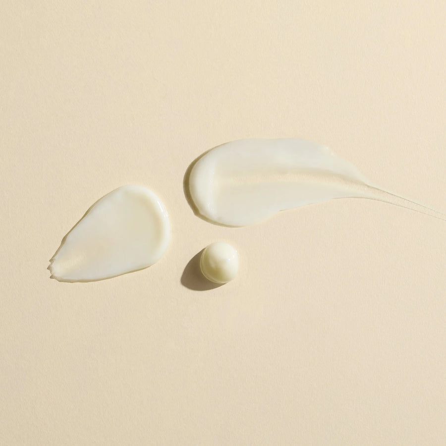Three droplets of Wildcraft Calm Lotion to show the lightweight texture of the product on a beige background
