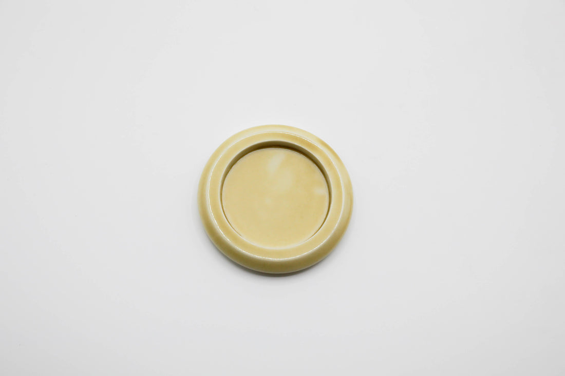 a small round, pale yellow ceramic plate on a light gray background