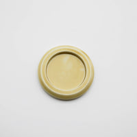 a small round, pale yellow ceramic plate on a light gray background