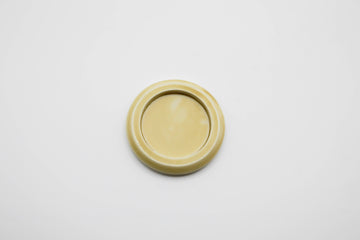 a small round, pale yellow ceramic plate on a light gray background