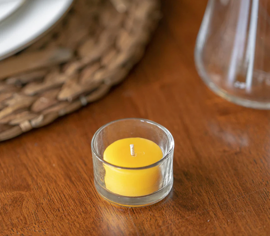 beeswax tea light in a glass cup on a table setting